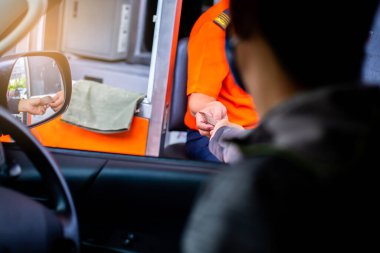 Sürücünün, ekspres yol parasını ödemesi için seçmeli odak noktası. Adam otoyol gişesi girişi için kasiyere para ödüyor. Yol boyunca el ödemesi ekspres geçiş ücreti. Hızlı ödeme yolu.