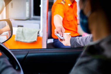 Sürücünün, ekspres yol parasını ödemesi için seçmeli odak noktası. Adam otoyol gişesi girişi için kasiyere para ödüyor. Yol boyunca el ödemesi ekspres geçiş ücreti. Hızlı ödeme yolu.