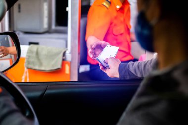 Sürücünün, ekspres yol parasını ödemesi için seçmeli odak noktası. Adam otoyol gişesi girişi için kasiyere para ödüyor. Yol boyunca el ödemesi ekspres geçiş ücreti. Hızlı ödeme yolu.