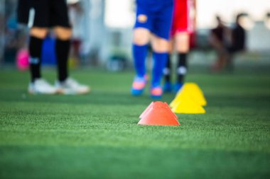 Bulanık futbol takımıyla koni işaretleyicisine seçici odak yeşil yapay sahada. Futbol akademisinin eğitim sınıfı..