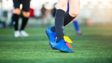 Eğitim için yeşil suni sahada koşan çocuk futbolcuların bacaklarına seçici odaklanma. Futbol ya da futbol akademisi.