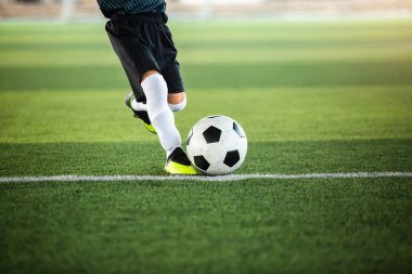 Çocuk futbolcunun hareket bulanıklığı ile futbola seçici bir odak noktası suni sahada onu vuruyor. Futbol maçı için futbolcu eğitimi.