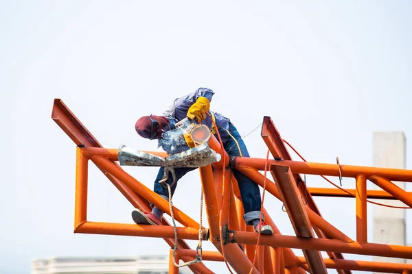 İnşaat alanındaki kaynakçılar. İşçi çelik yapıları kaynaklıyor. İşçiler de bir dizi sonbahar koruma cihazıyla yüksek irtifada çalışıyor.