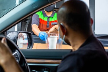 Tıbbi eldiven ve maske takan personelin müşteriye yemek vermesi için seçici bir odak noktası. Sür ve konsepti çıkar..
