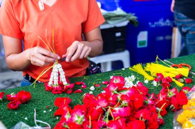 Asyalı kadın çalışanlar, Tayland 'daki Bangkok çiçek pazarında çiçek çelenkleri diziyorlar..