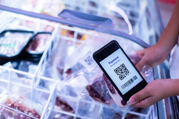 Süpermarkette dondurulmuş yiyeceklerle akıllı telefondaki QR kod etiketine seçici odak, bilgi ürünü ve çevrimiçi ödeme için QR kodunu tarayan müşteri.