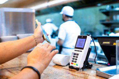Seçici odak noktası POS akıllı cihaz bulanık özel el tutuş akıllı telefon tarama için QR kodu ile restoranda geri planda şef kabul için para olmadan dijital ödeme üretmek.