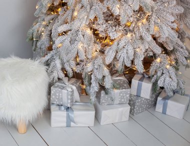 Oturma odasındaki Noel karlı ağacının yanında yerde yakın çekim Noel hediyeleri. Noel ışıkları ağaçta asılı. Yeni yıl. Noel ağacının üzerinde parıldayan çelenkler. İskandinav dekor odası