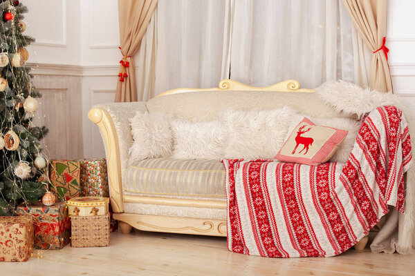 Classic Christmas living room interior with sofa and white pillows. Christmas at home. Beige sofa on background of decorated Christmas tree with gifts. Cozy Scandinavian interior room. New Year decor