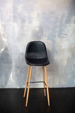 Bar taburesi gri beton bir duvarın karşısında duruyor. Çatı katı mobilya tasarımı. Modern siyah sandalye boş iç mekan, çimento duvar tasarımı arka planda duruyor. Çatı katının iç tarafında şık bir sandalye.. 