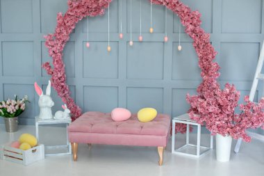 Pembe kanepede bahar evi, duvarda çiçek açan büyük sakura çelengi. Modern iç dekorasyon evi. Paskalya tarzı çocuk odası. Tavşanlı Paskalya dekorasyonu ve yumurtalı kutu.. 