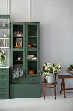 Sıcak ev dekorasyonu. Mobilyalarla dolu bir mutfak. Güzel bir buket çiçek, ahşap koltukta, dolapta. Bahçe işleri konsepti. Klasik bahçe aracı. Vazoda çiçekli şık yemekler.