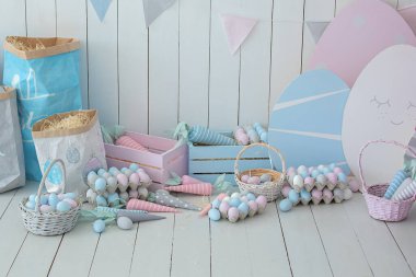 Bir sürü renkli Paskalya yumurtası ve havuç dolu sepetler! Bahar evi dekorasyonu ve Paskalya dekorasyonu. Tahta beyaz duvarda bayrak var. Paskalya tarzında çocuk odası. Renkli Paskalya odasının içi. 