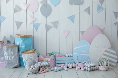 Paskalya odasının içi çok renkli. Bir sürü renkli Paskalya yumurtası ve havuç dolu sepetler! Bahar evi dekorasyonu ve Paskalya dekorasyonu. Tahta beyaz duvarda bayrak var. Paskalya tarzında çocuk odası.