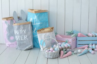 Ahşap zeminde bir sürü renkli Paskalya yumurtası ve havuç sepeti var! Paskalya odası dekorasyonu ve dekorasyonu. Bahar evi dekorasyonu. Paskalya odasının içi çok renkli. Paskalya tarzında çocuk odası. Eko Oyuncaklar. 