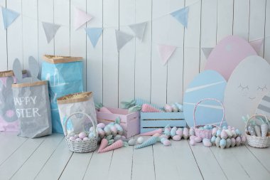 Bir sürü renkli Paskalya yumurtası ve havuç dolu sepetler! Bahar evi dekorasyonu ve Paskalya dekorasyonu. Tahta beyaz duvarda bayrak var. Paskalya tarzında çocuk odası. Renkli Paskalya odasının içi. 