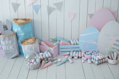 Paskalya odasının içi çok renkli. Bir sürü renkli Paskalya yumurtası ve havuç dolu sepetler! Bahar evi dekorasyonu ve Paskalya dekorasyonu. Tahta beyaz duvarda bayrak var. Paskalya tarzında çocuk odası.