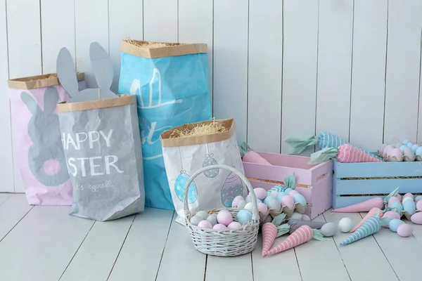 Ahşap zeminde bir sürü renkli Paskalya yumurtası ve havuç sepeti var! Paskalya odası dekorasyonu ve dekorasyonu. Bahar evi dekorasyonu. Paskalya odasının içi çok renkli. Paskalya tarzında çocuk odası. Eko Oyuncaklar. 