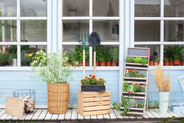 屋外的木制门廊 盒子里有绿色的植物和花朵 带着园艺工具 柳条篮和盆花回家 舒适的夏季装饰阳台的房子 园艺概念 街头露台 — 图库照片