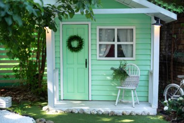 Bahçe mobilyalarıyla birlikte verandadaki ev. Sandalyesi ve sepet çiçekleri olan bir veranda evi. Yaz bahçesinin dış mekanı. Sonbahar tatili için dekore edilmiş cephe evi.. 