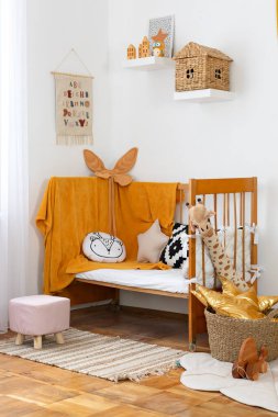 Çocuk odasının modern iç tasarımı. Anaokulu. Raflardaki bebek aksesuarları. Saf sarı İskandinav bebek odası: yatak, yastık, oyuncaklı sepet, puf ve yerde halı