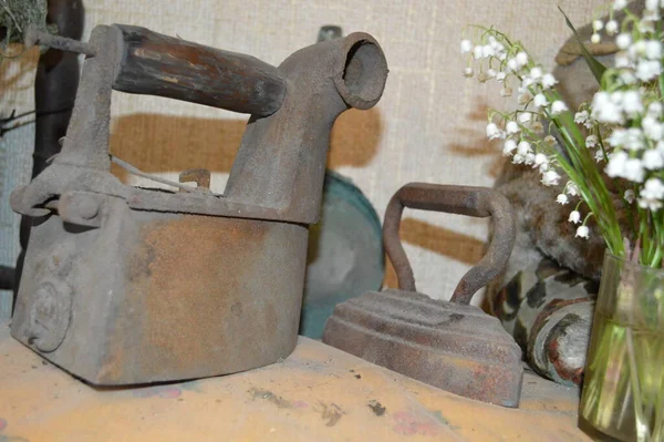 Masanın üzerinde eski demir demirler ve bir buket zambak var.