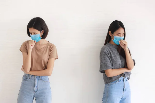 Two Asian teenage girls are Intimate friends wearing masks to new normal and social distancing to protect the spread of the coronavirus covid-19 on white background.