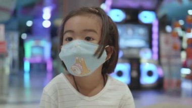 Asyalı şirin küçük kızın portresi Coronavirus 'u önlemek için yüz maskesi takıyor, COVID-19. Yeni normal kavram.