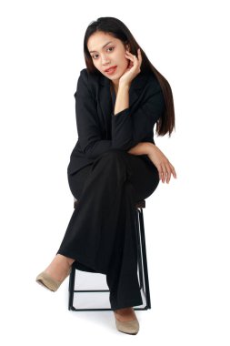 Uzun saçlı, güzel bir iş kadınının izole edilmiş portresi. Sandalyeye oturmuş beyaz arka plandaki kameraya bakıyor..