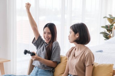 İki Asyalı kız arkadaş evde joysticklerle video oyunu oynamayı seviyor. Lezbiyen çiftler veya odada tatilde olan Igbt aktiviteleri.