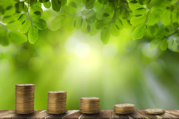 Step of coins on empty wooden table with green leaves bokeh background. start-up small business. saving and investment or family planning. growing your business along with the environment.