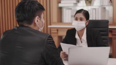 Asian young man wearing mask just graduated for job interview with the personnel department. The girl wears mask. Businessman and businesswoman discussing business plans in the midst of the COVID-19 