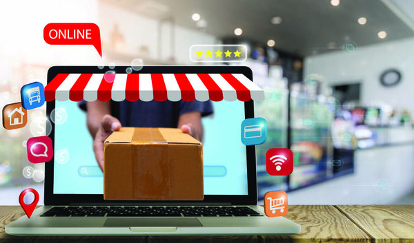 Delivery man sends parcels out of a laptop screen on a table in a supermarket. New normal and social distancing. E-commerce, market, and shopping online concept.