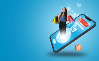 Elinde alışveriş poşeti tutan genç bir kadın mavi arka plandaki akıllı telefon dükkanında duruyor. Evden alışveriş. Yeni normal ve sosyal mesafeler. E-ticaret, piyasa ve çevrimiçi alışveriş kavramı.