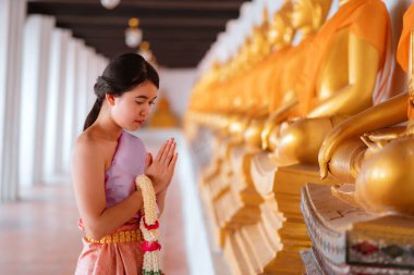 Tayland 'da düzenlenen Songkran Festivali sırasında Tayland kıyafeti giyen Asyalı kadınlar Buda heykellerine tapıyorlar. Tayland Yeni Yıl Günü. Tayland geleneği.