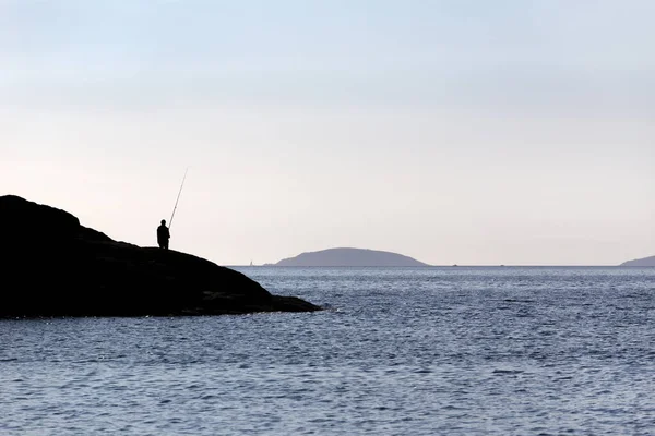 Silueta Pescador Pie Sobre Rocas Con Caña Pescar Cerca Del — Foto de Stock