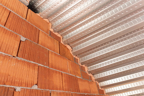 Roof detail with Metal decking sheet and brick wall on construction site. Composite decking for roofing. Construction industry