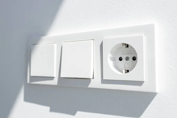 Modern White switch board with two switch and one european plug. European electrical outlet. Selective focus