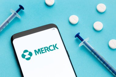 Galiçya, İspanya; 8 Haziran 2020: Merck logosunu ekranda, hapları ve şırıngayı mavi arka planda gösteren akıllı telefon