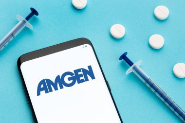 Galiçya, İspanya; 8 Haziran 2020: Ekranda Amgen logosu, mavi arka planda haplar ve şırıngayı gösteren akıllı telefon