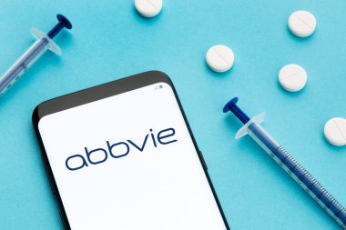 Galicia, Spain; June 8, 2020 : Smart phone showing Abbvie logo on screen and pills and syringe on blue background