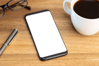 Smartphone mockup template with coffee cup and eyeglasses on wooden table. White screen