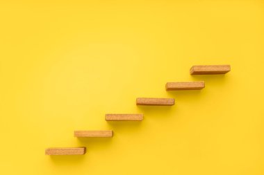 Sarı arka planda tahta merdiven. Büyüme, artan iş, başarı süreci konsepti. Boşluğu kopyala