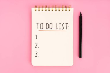 To do list in spiral notepad isolated on pink background. Top view