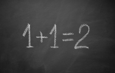 One plus one equals two hand written on chalkboard. Math simple equation. Top view