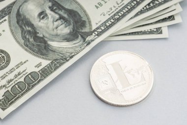 Litecoin madeni para ve bir yığın Amerikan doları banknot. Zincirleme paraya karşı fiat para kavramı