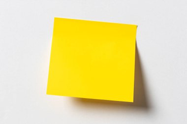 Beyaz duvardaki boş sarı yapışkan not. Şablon maketi