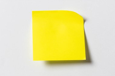 Beyaz duvardaki boş sarı yapışkan not. Şablon maketi