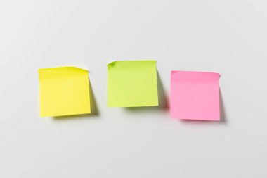 Beyaz duvarda üç tane boş renkli yapışkan not var. Şablon maketi