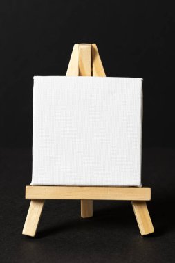 Koyu arkaplanda tahta sehpada boş bir beyaz tuval. şablon modellemesi